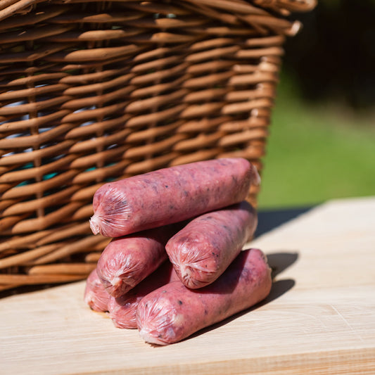 Glebe Farm Beef Sausage on a wooden surface with a wicker basket in the background.